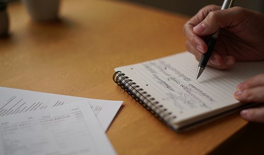 Крупный план рук психолога, заполняющего заметки во время сессии